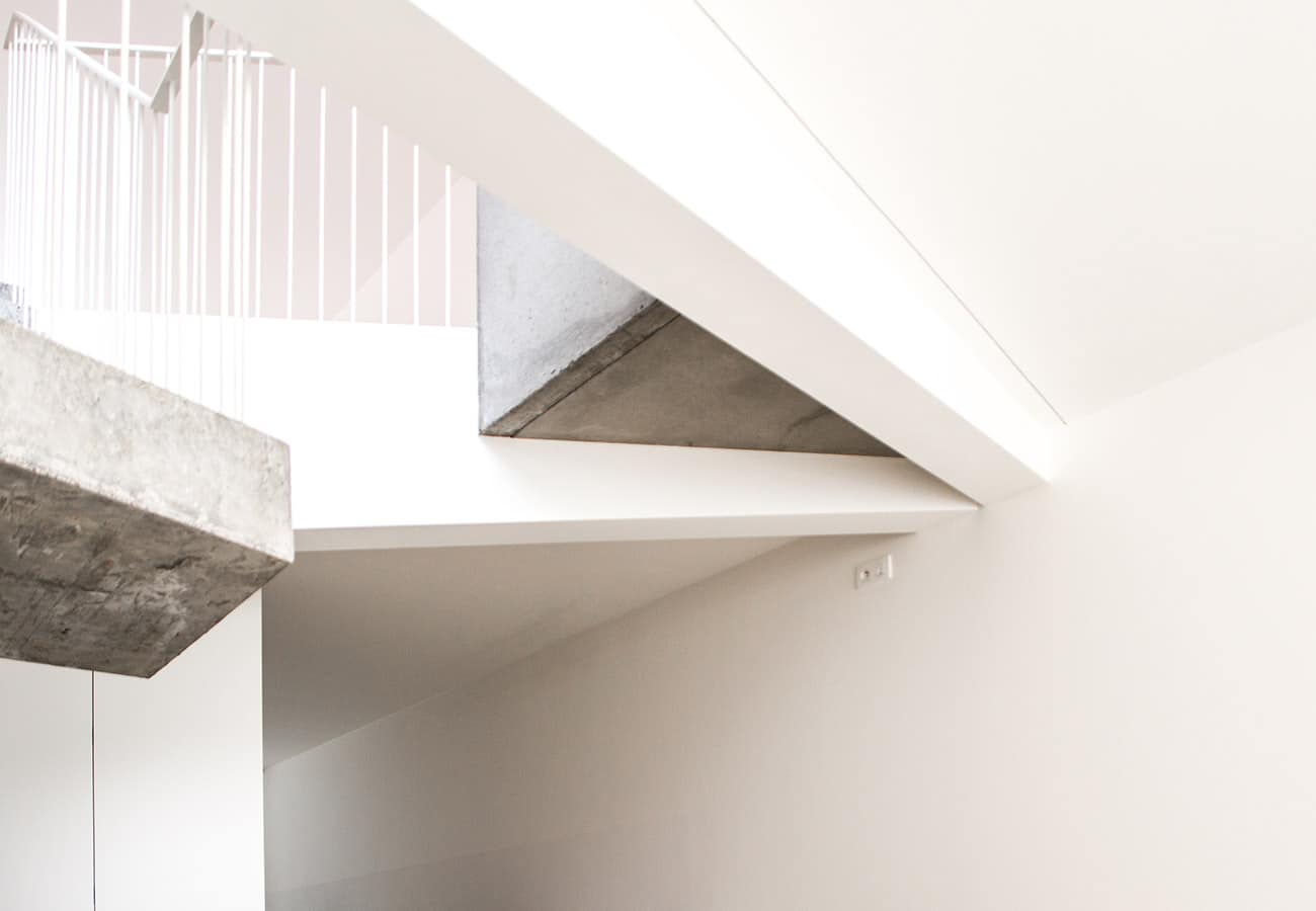 Detailfoto van een minimalistische betonnen trap in een moderne ruimte met witte muren door In't Kleur.