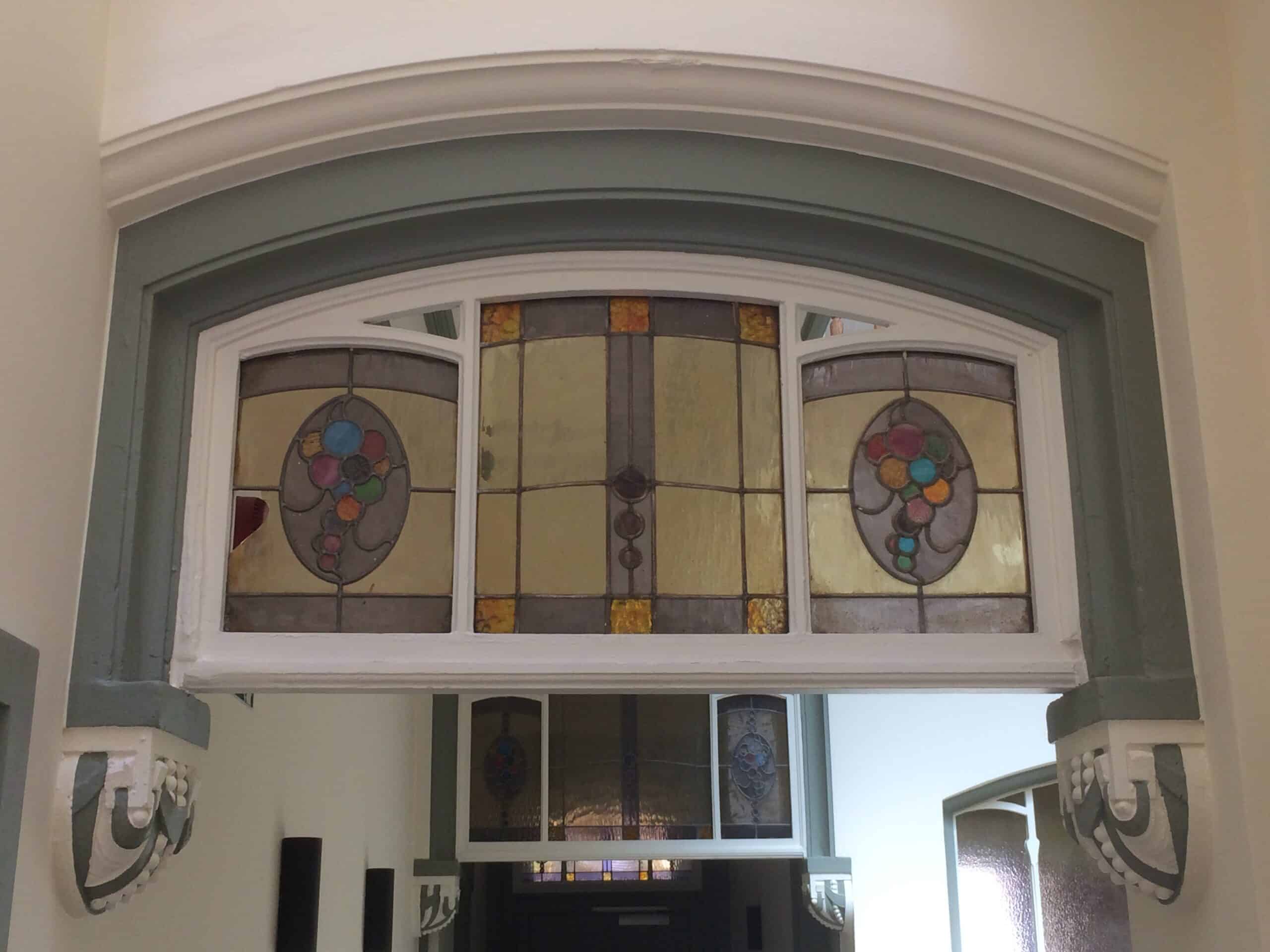 Glas-in-lood raam in art-nouveaustijl met kleurrijke bloemmotieven in Gent, geschilderde afwerking door In't Kleur.