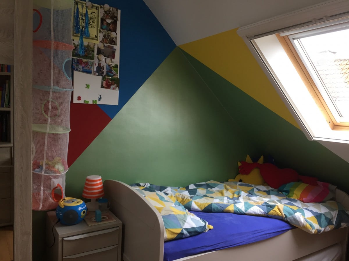 Kamer met kleurrijke geometrische muurschildering door In't Kleur en dakraam voor veel natuurlijk licht in Sle