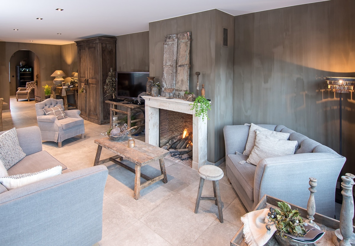 Landelijke woonkamer met open haard en rustieke meubels met een Gyproc afwerking door In't Kleur.
