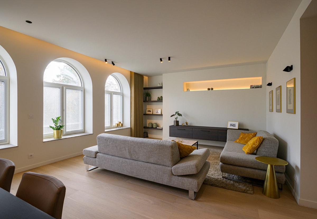 Sfeervolle woonkamer met een open indeling, en witte geschilderde muren door In't Kleur.