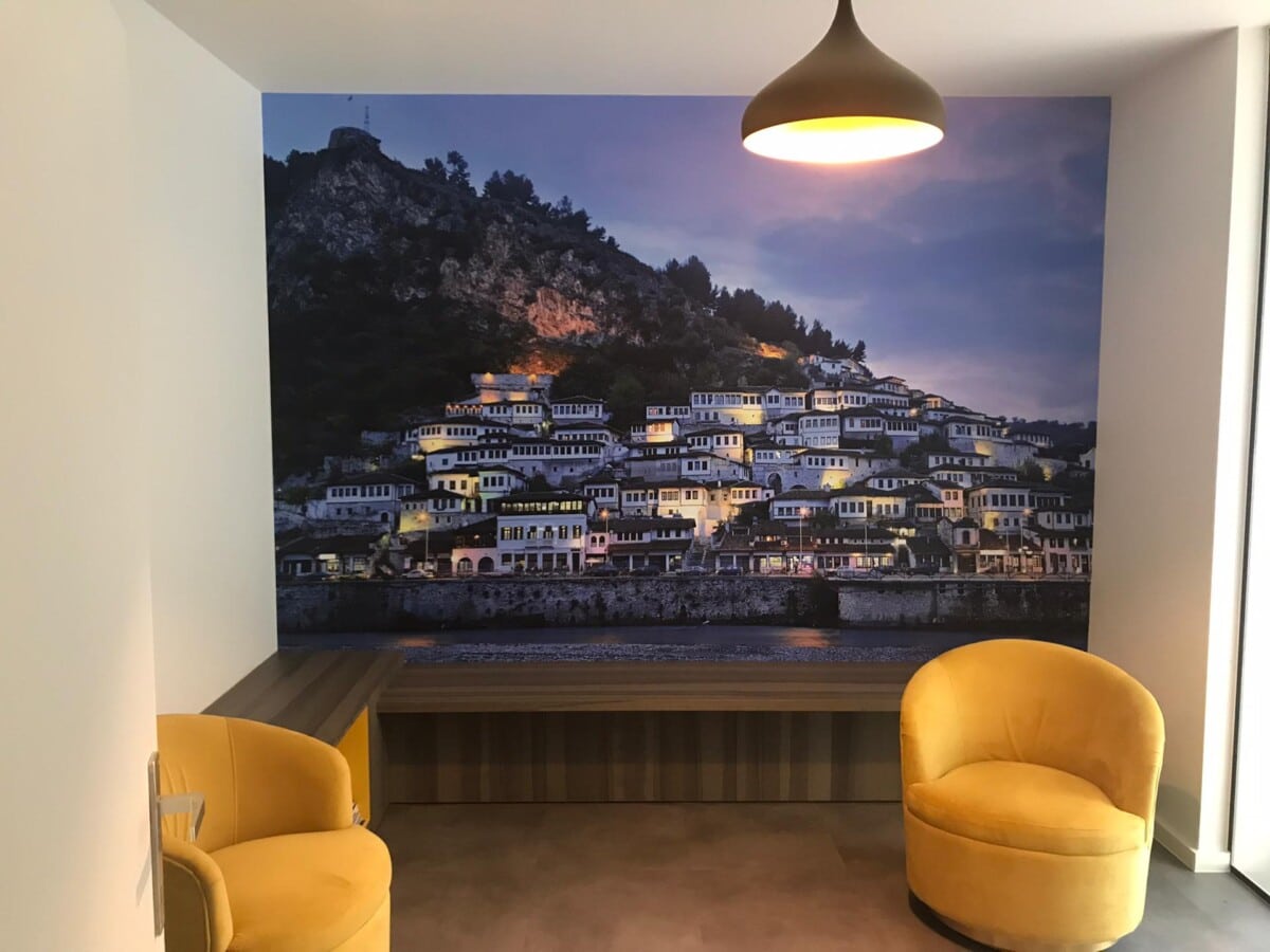 Zitruimte met twee gele fauteuils en een fotobehang van een schilderachtig stadje in de avond in Burst.