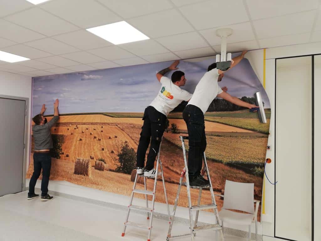 Airtex fotobehang van een historisch gebouw in Brugge, aangebracht op een muur in een modern gebouw door medewerkers van In't Kleur.