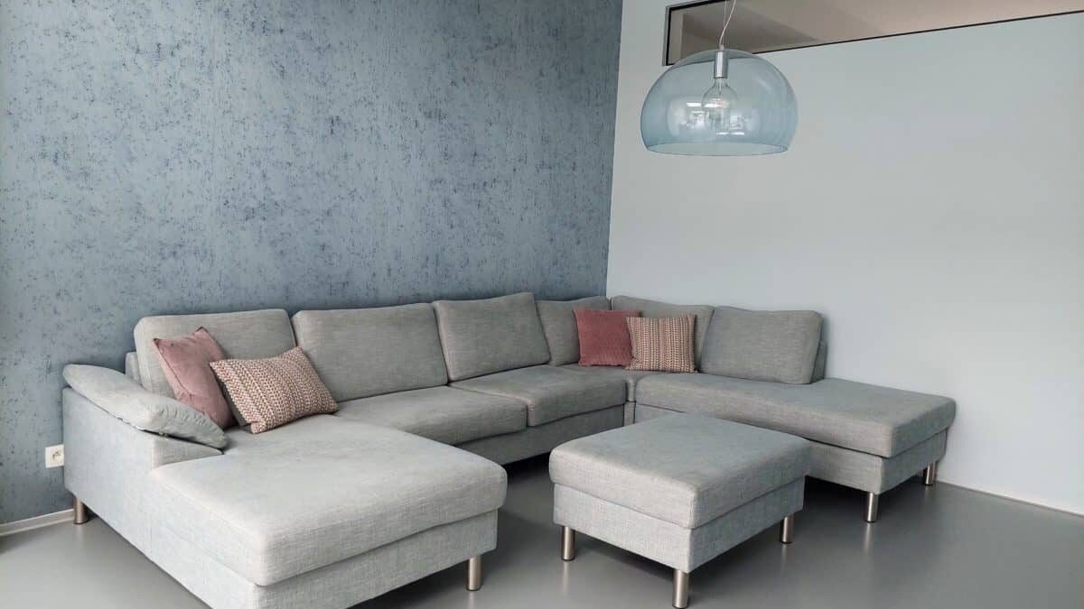 Gezellige zithoek met grijze hoekbank en pastel accentkussens voor een moderne look.