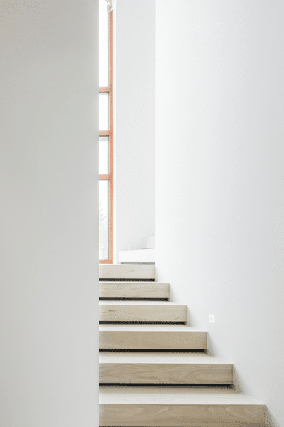 Minimalistische trap met licht houten treden en witte muren, geeft een strak en eigentijds gevoel.