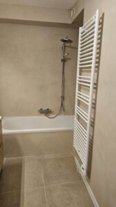 Een bad en warmte-element in een badkamer afgewerkt met mortex