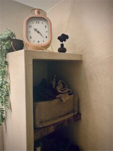 Een kastje met klok in een badkamer afgewerkt met mortex