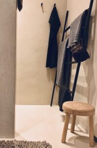 Een krukje en rek in een badkamer afgewerkt met mortex